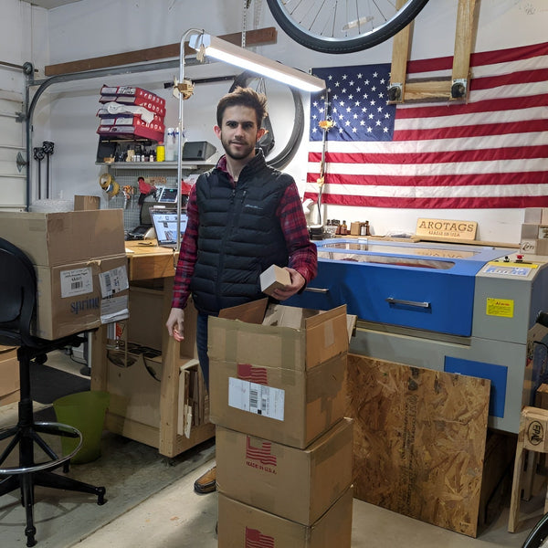 Man in a workshop with boxes and an American flag in the background
