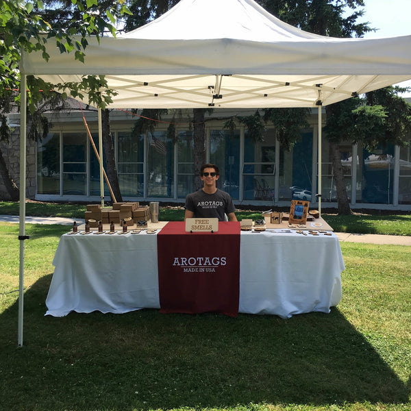 Person standing behind a table with 'Arotags' branding under a white tent outdoors.